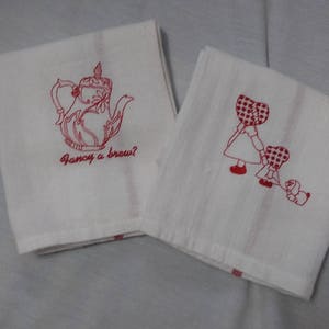 May include: Two white tea towels with red embroidered designs. One towel features a teapot with the text "Fancy a brew?" and the other towel features two girls in red and white gingham dresses with a dog.