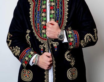 Può includere: Una giacca di velluto nero con ricami dorati intricati e accenti colorati. La giacca presenta un colletto alto e una chiusura con bottoni. Le maniche hanno un design ricamato simile.