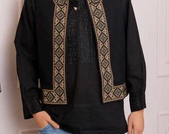 Può includere: Un gilet nero con un motivo geometrico dorato e nero. Il gilet ha un collo a V ed è indossato sopra una camicia nera a maniche lunghe.