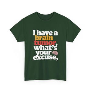 Può includere: T-shirt verde scuro con la scritta "I have a brain tumor, what's your excuse," in bianco, giallo e rosso. È inclusa una piccola grafica del cervello. La maglietta è a girocollo e maniche corte.