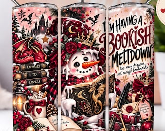 Puede incluir: Un vaso cilíndrico con un diseño festivo que muestra un muñeco de nieve, dragones, libros y elementos navideños. El texto dice I'M HAVING A BOOKISH MELTDOWN, too many dragons, not enough bookmarks y ENEMIES TO LOVERS. Incluye una pajita de metal.