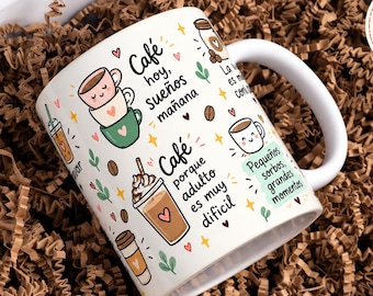 Puede incluir: Una taza de cerámica blanca con ilustraciones coloridas de varias bebidas de café, granos de café y hojas pequeñas. La taza muestra textos en español como "Café hoy, sueños mañana" y "Café porque adulto es muy difícil" junto a gráficos de tazas sonrientes.