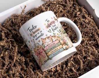 Puede incluir: Una taza de cerámica blanca con una ilustración colorida de un gato descansando sobre una pila de libros etiquetados Disciplina, Confianza, Constancia y Resultados, junto a un café helado y el texto en español Todo lo bueno llega en su momento.