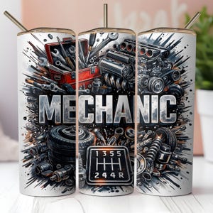 May include: A white tumbler with a mechanic theme. The design features the word "MECHANIC" in large, silver letters, surrounded by tools, car parts, and a gear shift pattern. A red toolbox and a car engine are also visible.