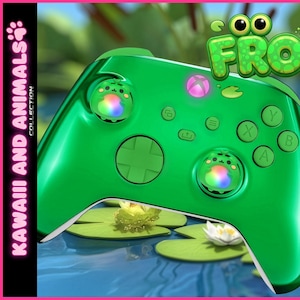 May include: Green video game controller with the word "Froggie" in a bubbly font. The controller has frog-themed accents and colorful lights. The background features cartoon frogs on lily pads.
