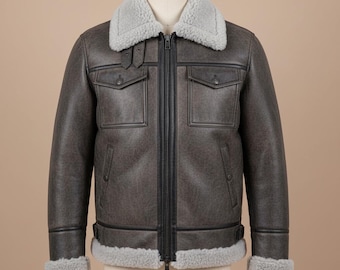 Puede incluir: Chaqueta de cuero gris con cuello y ribete de borrego gris. La chaqueta tiene cremallera, dos bolsillos en el pecho y dos bolsillos laterales. La chaqueta se exhibe en un maniquí.
