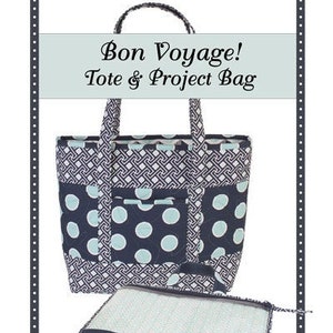 May include: A quilted tote and project bag set. The tote bag features a navy blue and white geometric pattern with navy blue polka dot accents. The set includes a coordinating project bag. The text "Bon Voyage! Tote & Project Bag" is displayed.