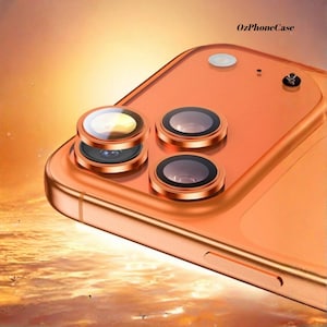 Puede incluir: Primer plano de un smartphone de color cobre con tres lentes de cámara y un flash. El teléfono tiene un acabado brillante y el texto "OzPhoneCase" es visible. El fondo tiene un degradado naranja.