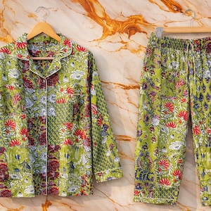 Peut inclure: Ensemble de pyjama vert à motifs floraux, composé d'une chemise boutonnée et d'un pantalon assorti. L'ensemble présente un motif vibrant de fleurs rouges, blanches et bleues sur fond vert. La chemise a un col et des manches longues.
