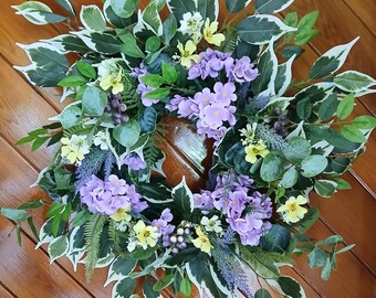 Ghirlanda primaverile/estiva di fiori viola per la porta. Decorazione artificiale con violette viola e fiori gialli. Ghirlanda regalo per una nuova casa.