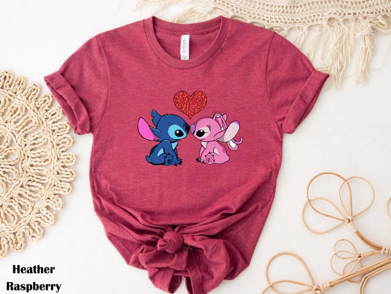 A red t-shirt with a graphic of two cartoon characters, a blue one and a pink one, standing close together and holding a heart.