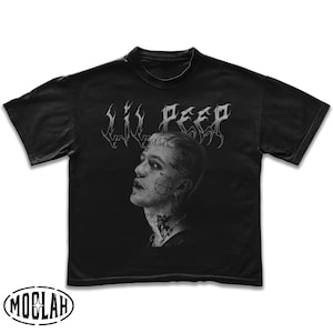 May include: Black t-shirt featuring a portrait of Lil Peep with the text "Lil Peep" above the image. The shirt has a crew neck and short sleeves. The Moblah logo is at the bottom.