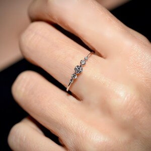 May include: A delicate silver ring with five small round diamonds set in a row.