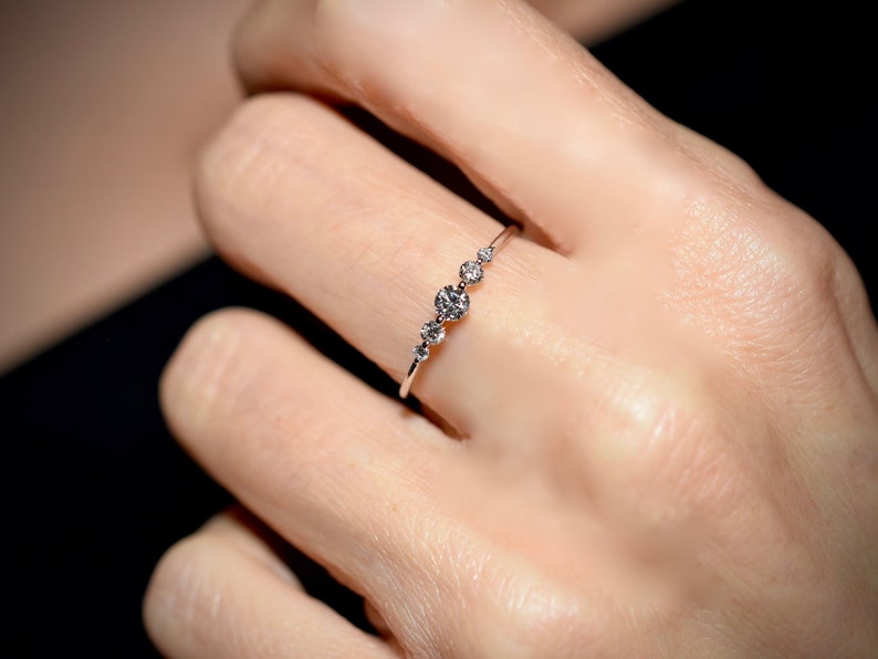 May include: A delicate silver ring with five small round diamonds set in a row.