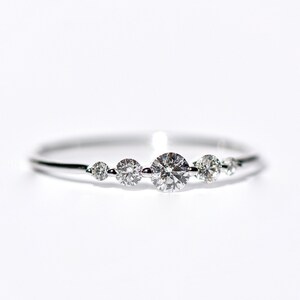 May include: A delicate silver ring with five small round diamonds set in a row.