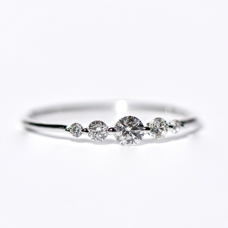 May include: A delicate silver ring with five small round diamonds set in a row.