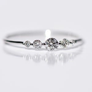 May include: A delicate silver ring with five small round diamonds set in a row.