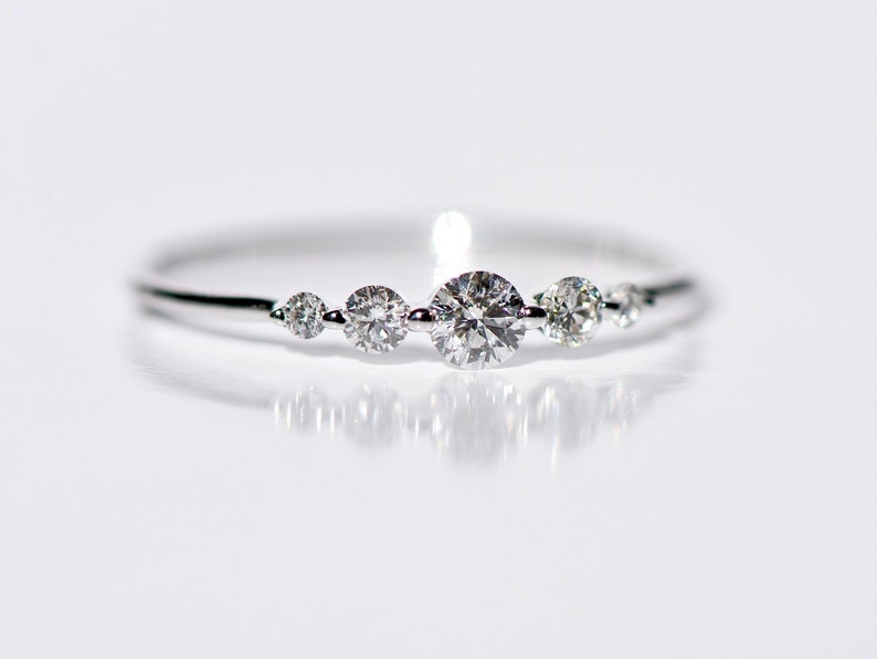 May include: A delicate silver ring with five small round diamonds set in a row.