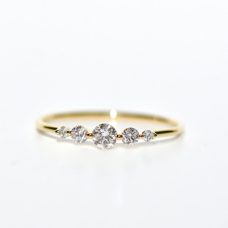 May include: A delicate gold band ring with five small round diamonds set in a row.