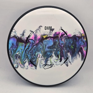 May include: A white disc golf disc with a black rim. The disc features a colorful, marbled design in shades of blue, purple, and yellow. The text "OHM" and "2 5 0 1 PUTT/APPROACH" are printed on the disc, along with the MVP Disc Sports logo.