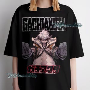 May include: Black t-shirt featuring a graphic of an anime character with white hair and chains. The text "GACHIAKUTA" is above the character, and Japanese text is below. The shirt is a loose fit.