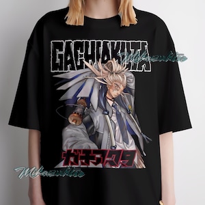 May include: Black t-shirt featuring a graphic of an anime character with the text "GACHIAKUTA" in a bold, stylized font above the character and Japanese text below. The character is depicted in a dynamic pose.