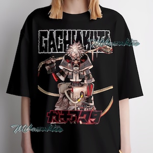 May include: Black t-shirt featuring a detailed anime-style illustration of a character with a mask, holding a weapon. The shirt has the text "GACHIAKUTA" in a bold, stylized font above the character and Japanese text below.