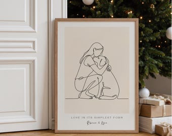 May include: A framed print featuring a minimalist line drawing of a person embracing a dog. The artwork is in black against a beige background, with the text "LOVE IN ITS SIMPLEST FORM" and the names "Rebecca & Kyra" at the bottom. The frame is light brown.