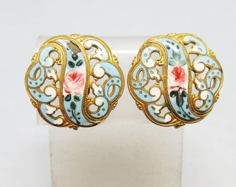 May include: A pair of gold tone clip-on earrings with a blue and white enamel design and pink roses.