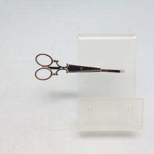 May include: Silver-toned scissor-shaped hair clip with ornate details.