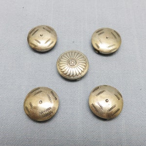 May include: Five silver-toned buttons with intricate designs. The buttons have a circular shape and feature a variety of patterns, including a floral motif and a geometric design.