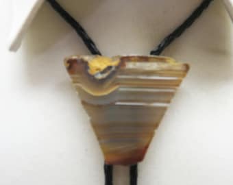 May include: A brown and white agate stone bolo tie with a black cord. The stone is in a triangular shape with a rough edge.