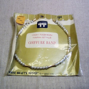 May include: A white pearl headband with gold accents. The packaging says "Tip-Top High Fashion Tiara-Style Coiffure Band".