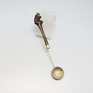 May include: A wooden spoon with a carved bear head handle and a silver bowl. The bowl has a design of a bear on it.