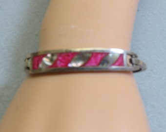 May include: A silver bangle bracelet with a pink and white inlay design.
