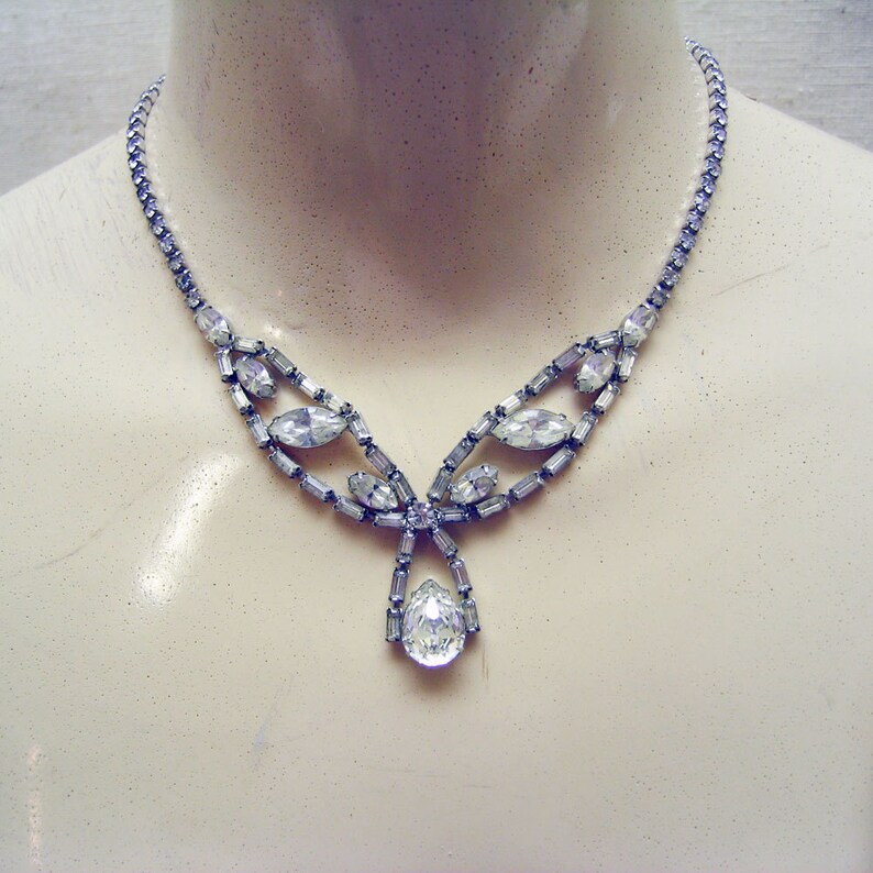 Op de afbeelding: Een zilveren ketting met een traanvormige hanger en een delicaat ontwerp van heldere strass.