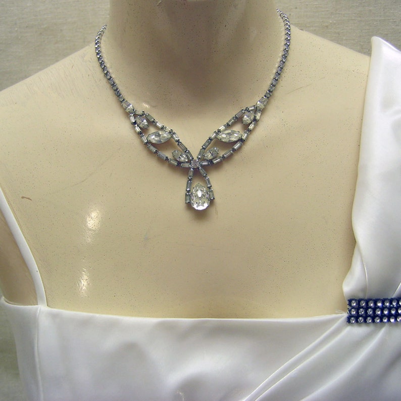 Op de afbeelding: Een zilveren ketting met een traanvormige hanger en een delicaat ontwerp van heldere strass.