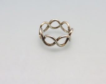 May include: A silver ring with a twisted, interwoven design. The ring is made of a single piece of metal that is twisted and woven together to create a unique and intricate design.