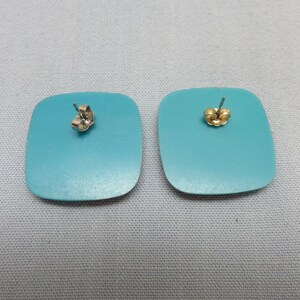 Op de afbeelding: Een paar turquoise vierkante oorbellen met zilveren oorhaakjes.