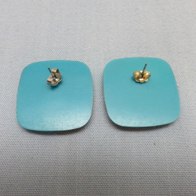 Op de afbeelding: Een paar turquoise vierkante oorbellen met zilveren oorhaakjes.