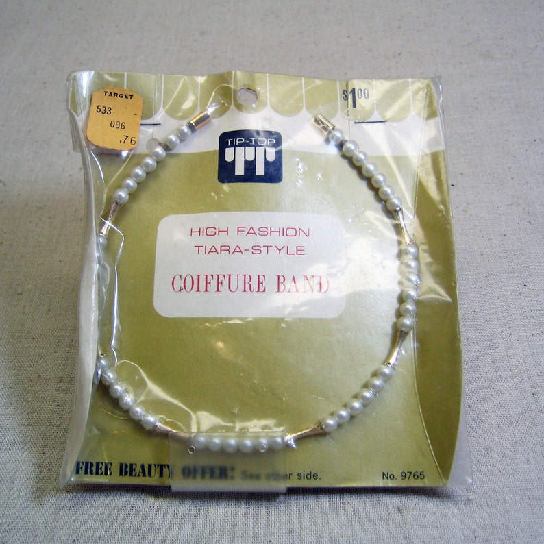 May include: A white pearl and gold tiara-style hair band on a yellow and white packaging card. The card reads "Tip-Top High Fashion Tiara-Style Coiffure Band" and "Free Beauty Offer! See other side. No. 9765".