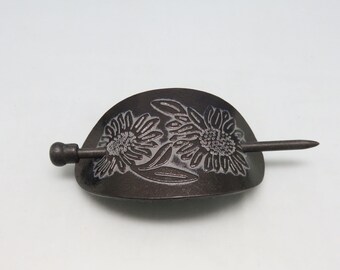 May include: A black wooden hair stick with a carved design of two sunflowers. The stick is about 4 inches long and has a rounded end.