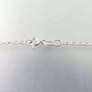 K&ouml;nnte beinhalten: Nahaufnahme eines silbernen Kettenhalsbandverschlusses. Der Verschluss ist ein Karabinerverschluss mit einem kleinen Verbindungsring.