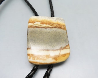 May include: A bolo tie with a brown leather cord and a large, rectangular stone pendant. The stone is a light brown, white, and gray color with a striped pattern.