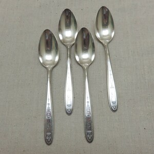 May include: Four silver teaspoons with ornate designs on the handles.