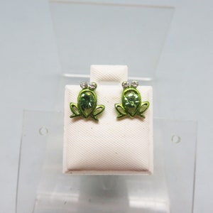 May include: A pair of green frog stud earrings with clear rhinestone accents.