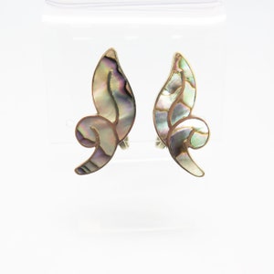 May include: A pair of silver tone clip-on earrings with a swirl design made of iridescent abalone shell.