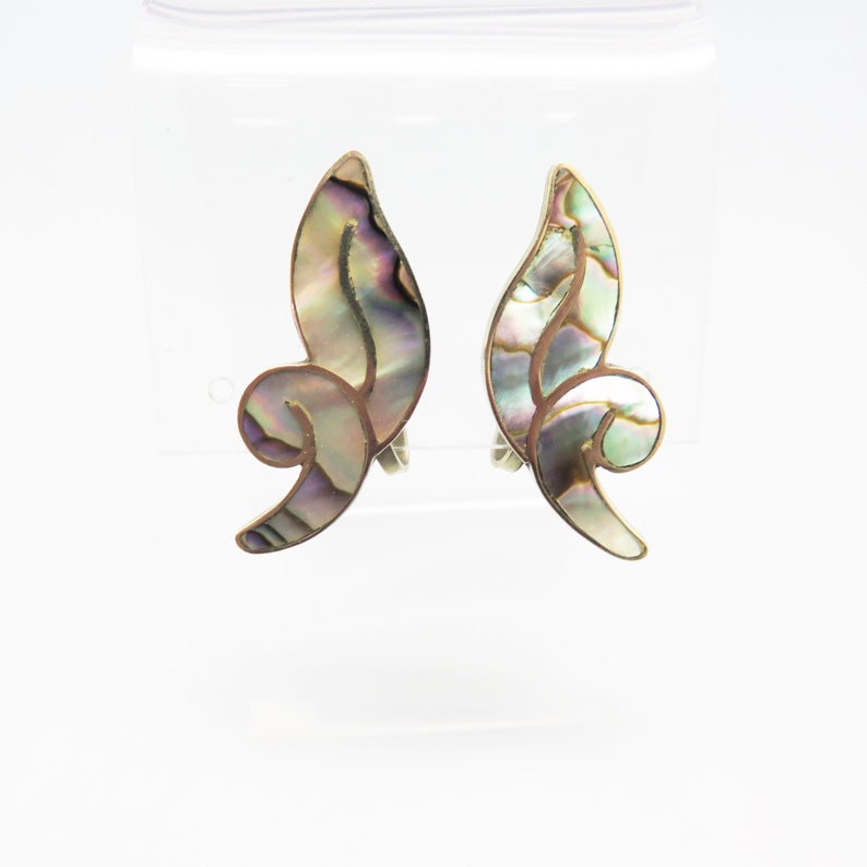 May include: A pair of silver tone clip-on earrings with a swirl design made of iridescent abalone shell.