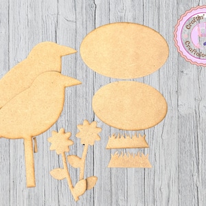 May include: A collection of unfinished wooden cutouts, including two bird shapes, two oval shapes, two flower shapes, and two grass shapes. The pieces are light brown and arranged on a light gray wooden surface. A pink and purple logo is in the upper right corner.