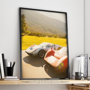 Peut inclure: Impression encadrée de deux voitures de course vintage, une blanche et une orange, sur une route. Le fond montre un champ jaune et des montagnes sous un ciel ensoleillé. Le texte "COLOR & BLACK-WHITE" est en bas.